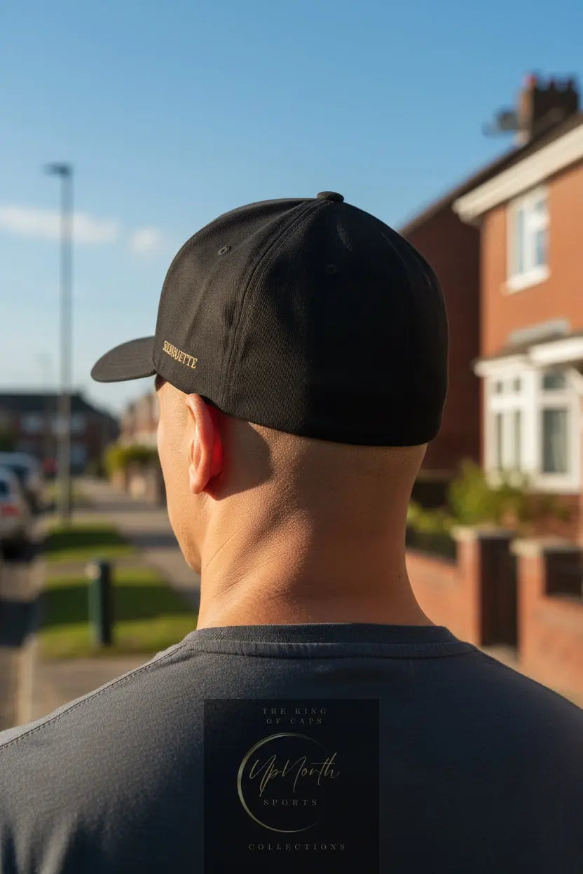 A male model viewed from behind wearing a black Silhouette baseball cap with gold embroidered logo - Paparazzi Original