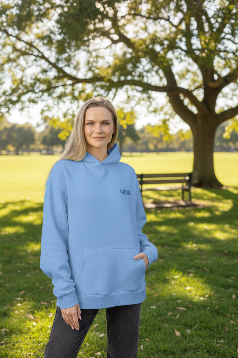 Woman wearing a light blue hoodie with a Paparazzi logo on left chest